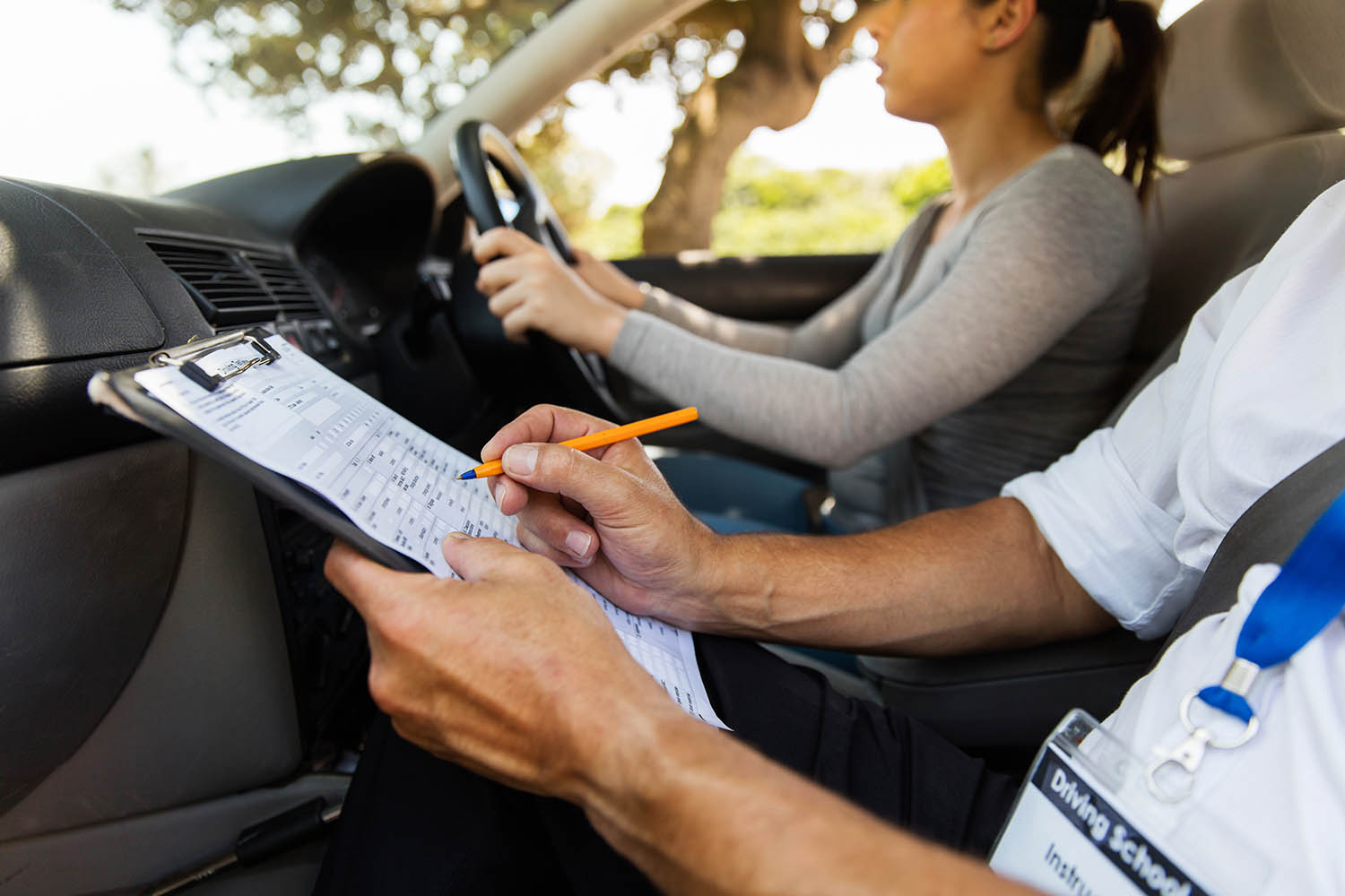 driving instructor inside a car with student driver doing checklist